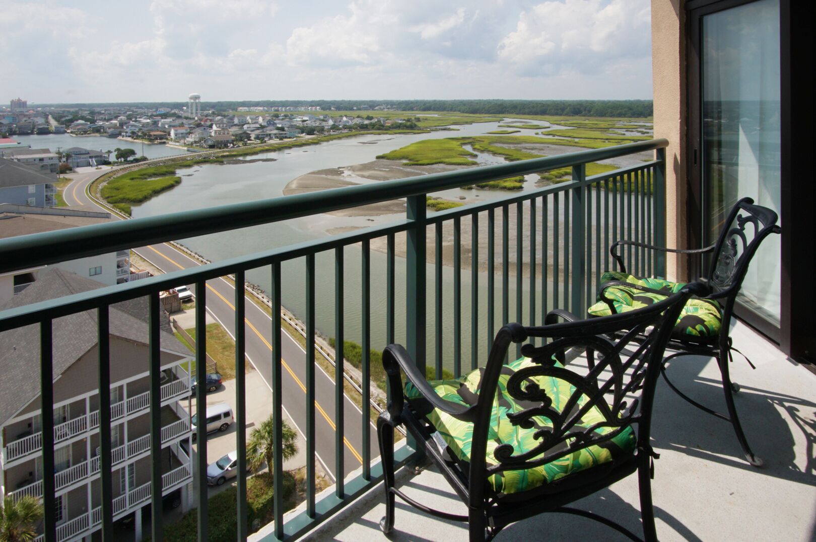 A balcony with two chairs, a view of a river, and a cityscape in the background.