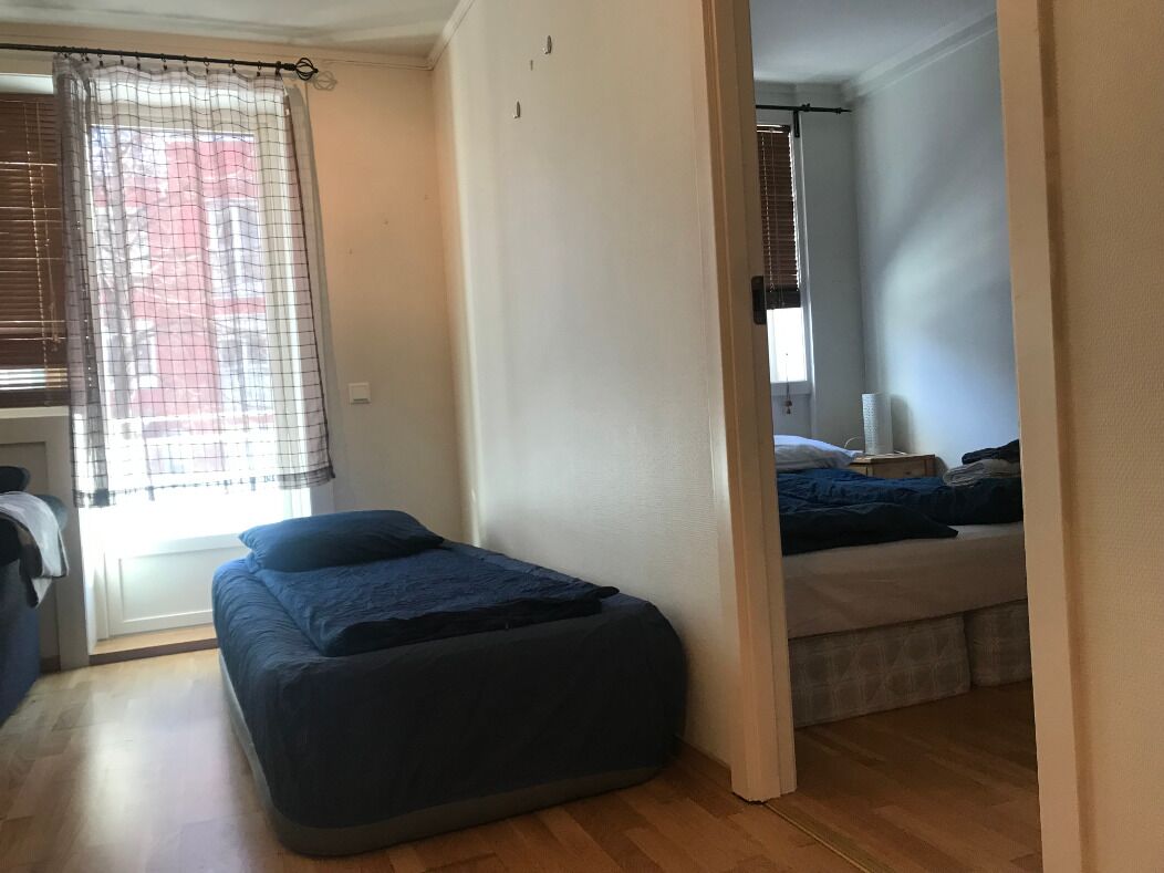 A room with a bed, a small seating area, and a window with curtains.