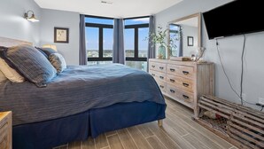 A bedroom with a large bed, a dresser, a mirror, and a TV. - Updated condo with amazing oceanfront view. Pool, sundeck, balconies perfect for couples or families (North Myrtle Beach)