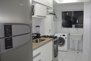A compact kitchen with a stainless steel refrigerator, a built-in washing machine, a coffee maker, and a sink. - Sun Paradise - Beautiful 4 bedroom apartment by the sea (2) (Ponta Verde)