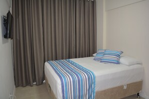 A bedroom with a bed, a TV, and curtains. - Sun Paradise - Beautiful 4 bedroom apartment by the sea (2) (Ponta Verde)