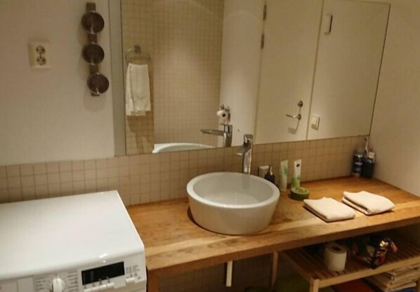 A bathroom with a white sink, a mirror, a towel rack, and a wooden countertop.