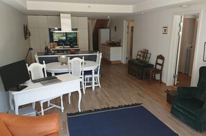 Ett kompakt bostadsutrymme med en matplats, ett kök och en sittgrupp med en soffa och en fåtölj.