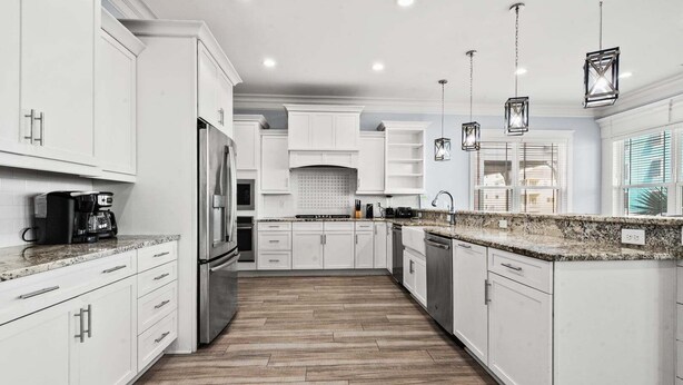 A modern kitchen with white cabinetry, a stainless steel refrigerator, a coffee maker, and pendant lighting. - Luxe boulevard home w/private pool, elevator, outdoor kitchen-purely wonderful! (North Myrtle Beach)