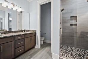 Ein Badezimmer mit Dusche, Waschbecken inklusive Spiegel und Toilette.