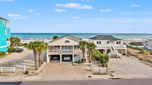 A beachfront property with a two-story building, a covered parking area, and a view of the ocean. - Luxe boulevard home w/private pool, elevator, outdoor kitchen-purely wonderful! (North Myrtle Beach)