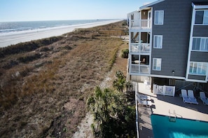 A beachfront property with a pool, outdoor seating, and a view of the beach.