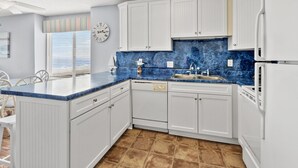 A kitchen with white cabinets, a blue marble countertop, and a clock on the wall.