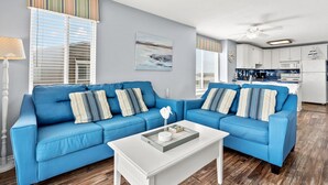 A living room with a blue sofa, white coffee table, and striped pillows.