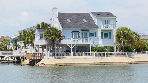 Une maison située au bord de l’eau, dotée d’un balcon, d’une véranda et d’un quai.