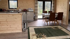 A wooden cabin interior with a kitchen, dining area, and skylights. - Smiddyhill Lodge, Innerleithen self catering holiday let (Innerleithen)