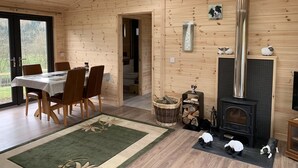 A wooden cabin interior with a dining area, a fireplace, and a skylight. - Smiddyhill Lodge, Innerleithen self catering holiday let (Innerleithen)