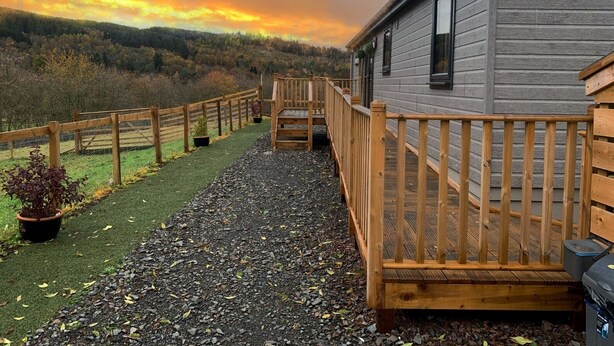 A wooden deck leading to a cabin with a view of a forested hillside. - Smiddyhill Lodge, Innerleithen self catering holiday let (Innerleithen)