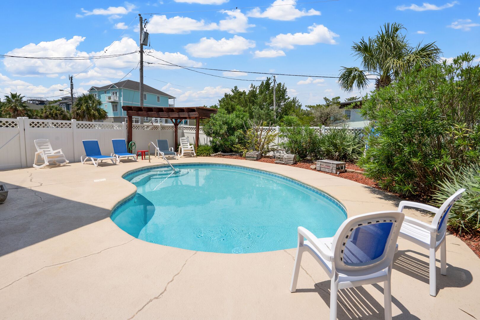 A swimming pool with lounge chairs and a pergola.