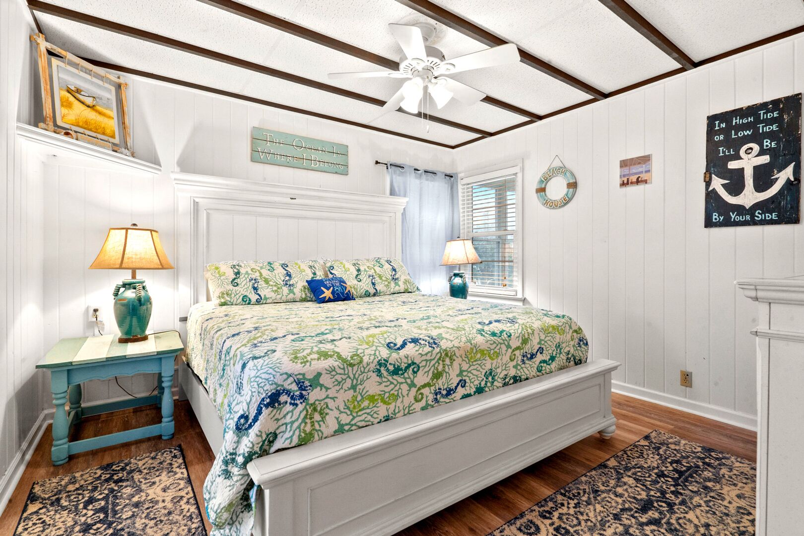 A bedroom with a bed, two nightstands, a ceiling fan, and a window with blinds.