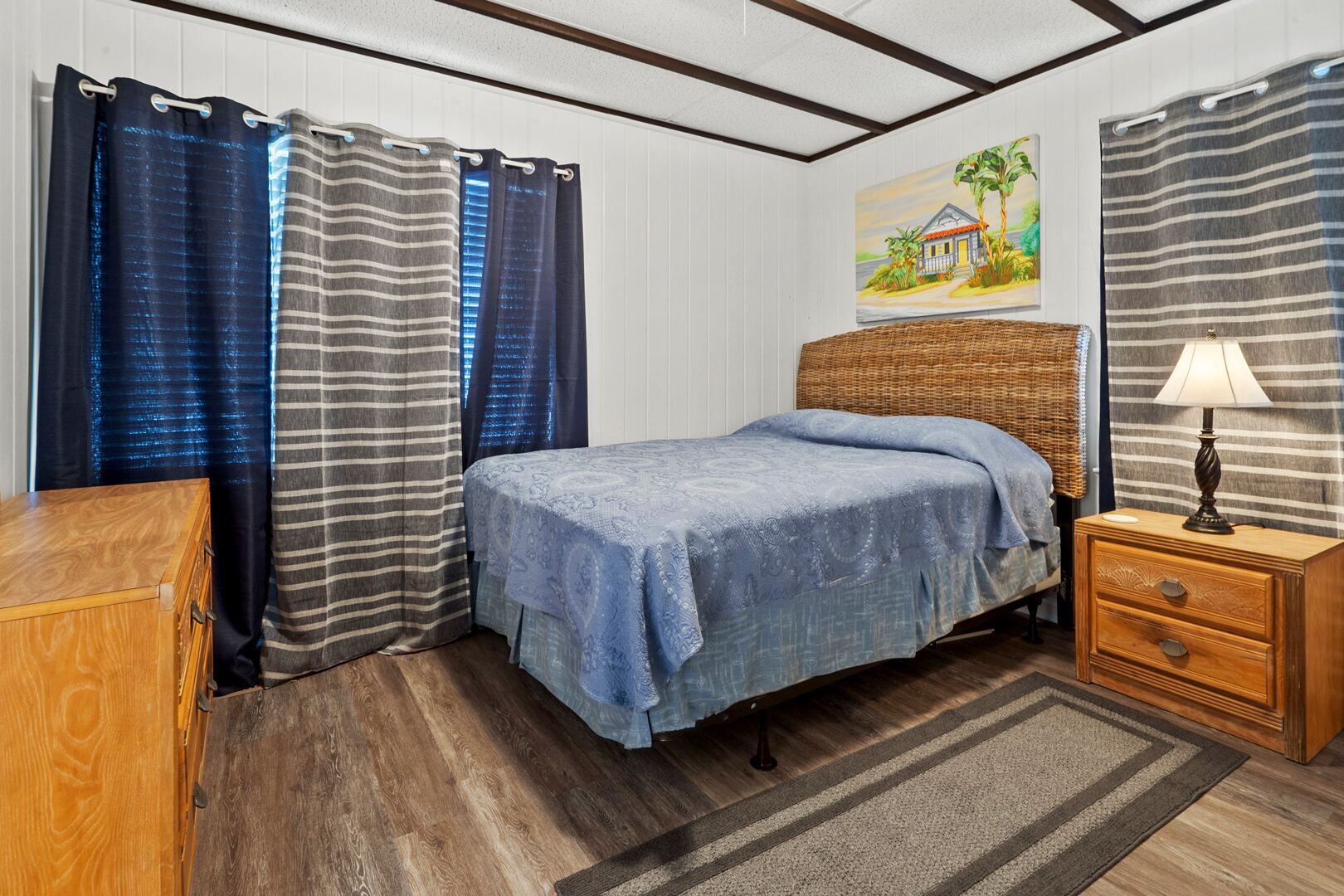 A bedroom with a bed, wooden nightstand, and a painting on the wall.