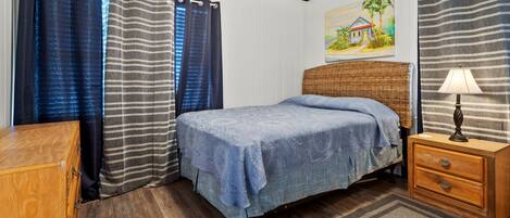 A bedroom with a bed, wooden nightstand, and a painting on the wall.