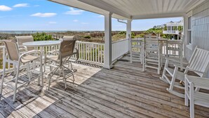 Eine überdachte Terrasse im Freien mit weißer Möbel und Blick auf den Strand.