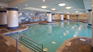 Une piscine intérieure ornée d’une fresque représentant des dauphins, avec des murs carrelés et une zone de baignade aux eaux cristallines.