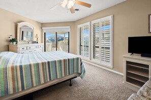 A bedroom with a bed, dresser, TV stand, and a balcony with shutters. - Cozy Boulevard condo--across street from ocean w/pool, sundeck, grill--waiting for your family! (North Myrtle Beach)