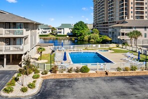A hotel with a swimming pool, lounge chairs, and a view of a lake. - Cozy Boulevard condo--across street from ocean w/pool, sundeck, grill--waiting for your family! (North Myrtle Beach)