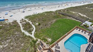 A beach resort with a swimming pool, a walking path, and a view of the beach.