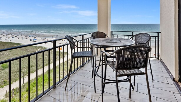 A balcony with a view of the beach and ocean.