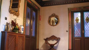 Une pièce comprenant un banc en bois, un miroir et un meuble contenant des objets décoratifs.