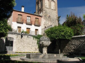 A historic building with a stone facade, a clock tower, and a fountain in the courtyard. - Apartahotel santa Marina (Cuellar)
