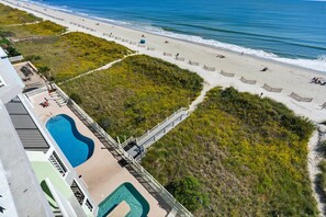 A resort with a swimming pool, beach access, and a view of the ocean.