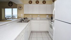 A kitchen with white cabinets, a sink, a toaster, and a refrigerator.