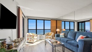 A modern living room with a large window, a sofa, a chair, and a coffee table.