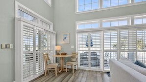 A spacious room with a large window, a round table with chairs, and a sofa. - Elegant luxury channel home w/plenty of relaxing space inside & out-deck, floating dock, grill (North Myrtle Beach)