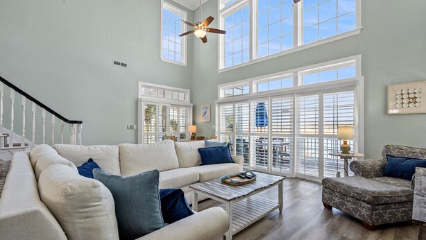 A spacious living room with a high ceiling, large windows, and a staircase. - Elegant luxury channel home w/plenty of relaxing space inside & out-deck, floating dock, grill (North Myrtle Beach)