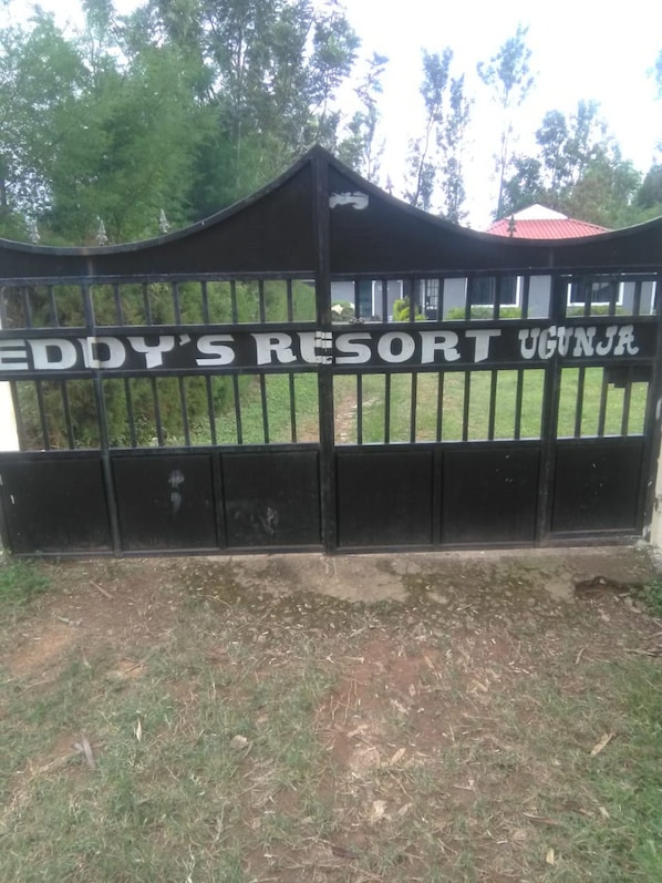 A black metal gate with the text "EDDY'S RESORT UGANJA" on it.