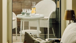 A balcony with a table set for two, a wicker chair, and a view of the sea. - The Ivens, Autograph Collection (Lisbon)