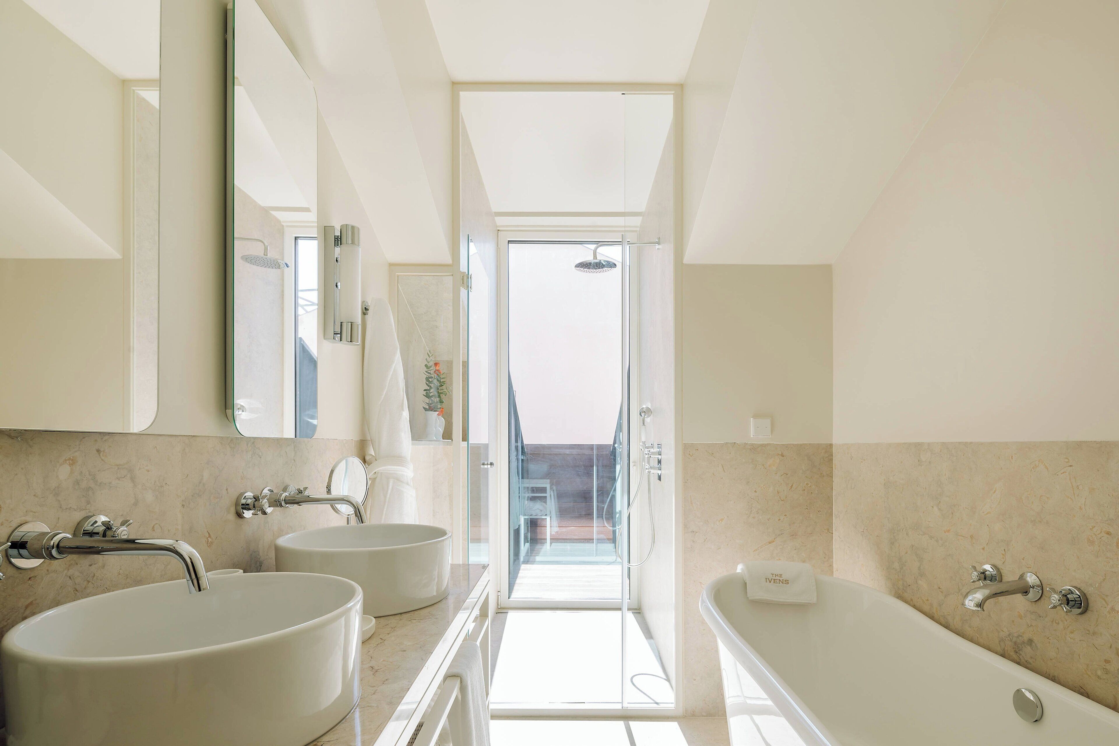 Een moderne badkamer met twee wastafels, een badkuip en een douche.