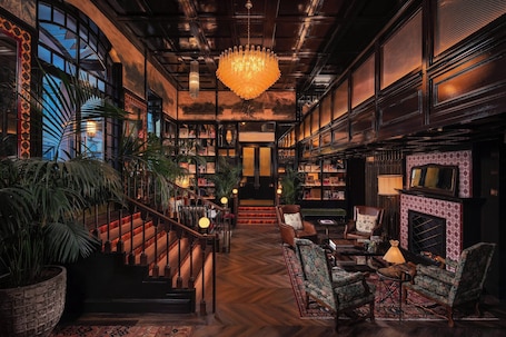 A spacious lobby with a grand staircase, a large chandelier, and a fireplace.