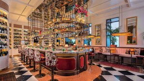 A bar area with multiple shelves of bottles, a central bar counter, and seating arrangements. - The Ivens, Autograph Collection (Lisbon)