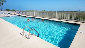 A swimming pool with clear blue water, a white fence, and a lifeguard stand.