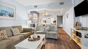 A living room with a sofa, patterned chairs, a coffee table, and a TV.