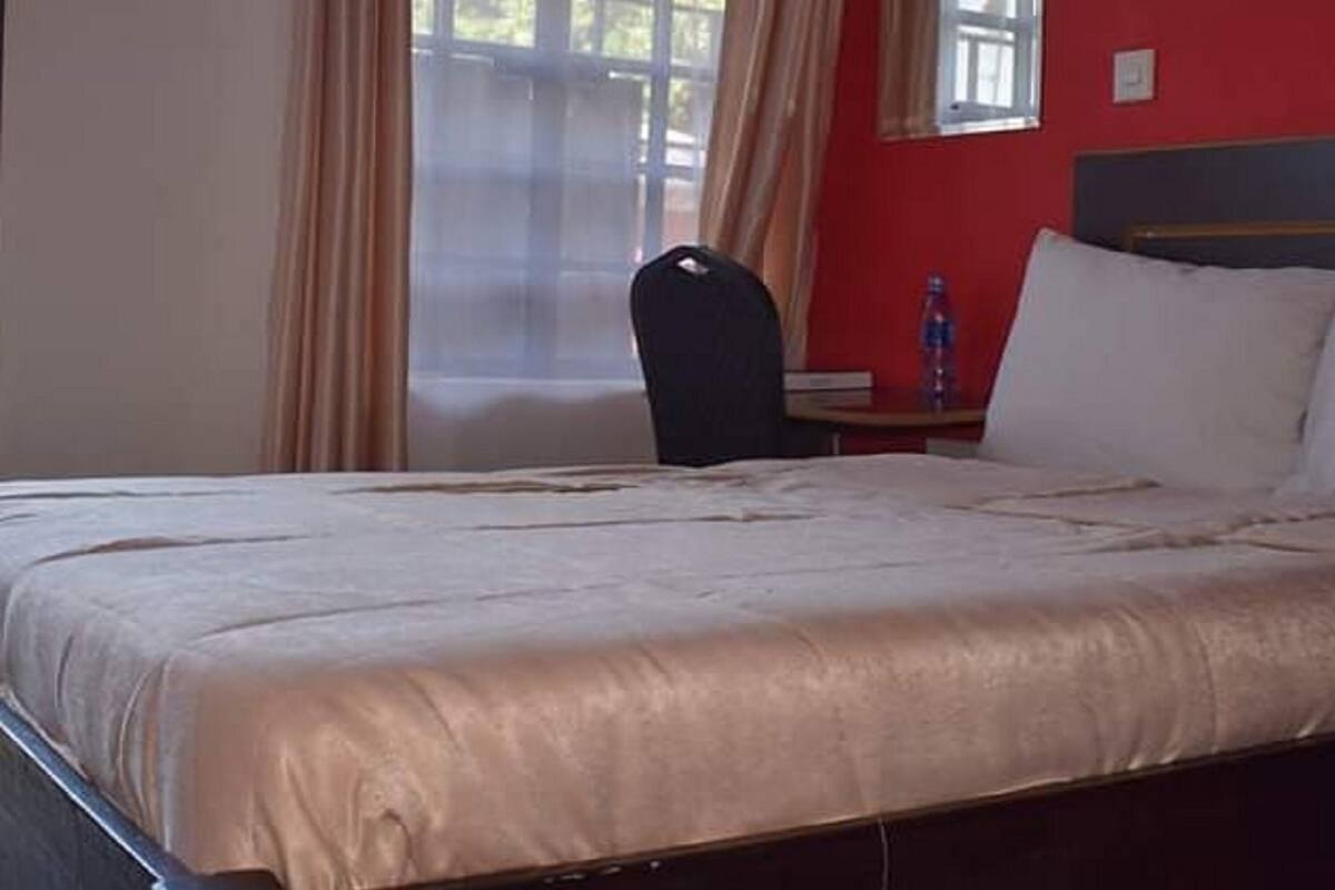 Una habitación de hotel con una cama, una silla, una mesita y una ventana con cortinas.