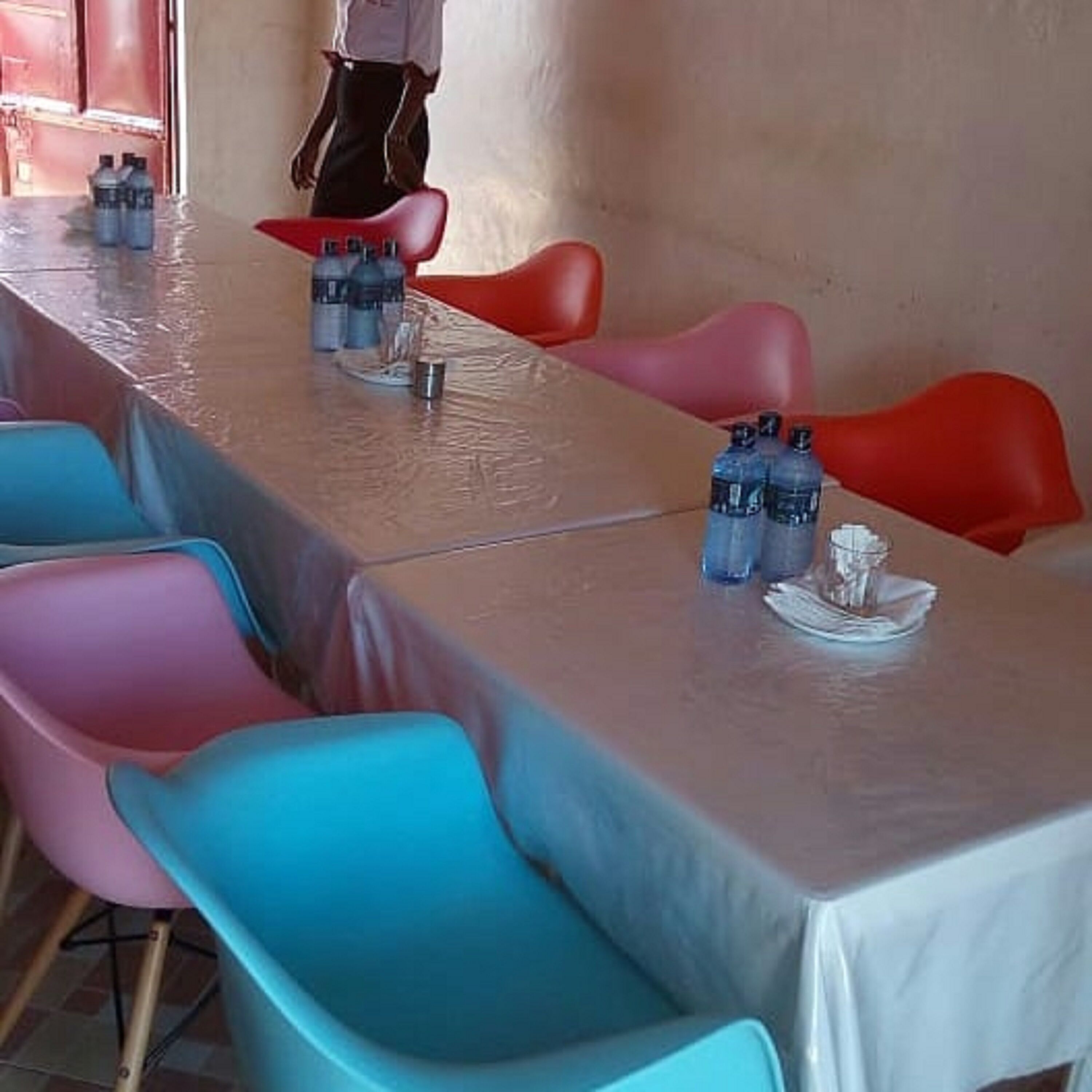 A conference room with a long table, colorful chairs, and water bottles on the table.