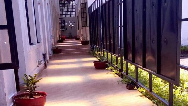 A corridor with tiled flooring, potted plants, and a metal fence. - Dover Hotel Bondo (Bondo)