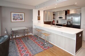 A modern kitchen with a white countertop, stainless steel appliances, and a dining area with a table and chairs.