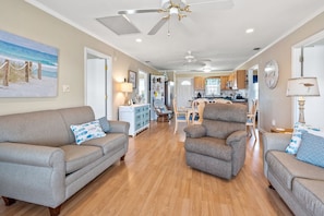 Relax in this inviting living area with a high ceiling and ceiling fans, featuring two sofas and a dining area.