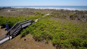 Een strand met een houten trap die naar de kust leidt, omringd door weelderige begroeiing.