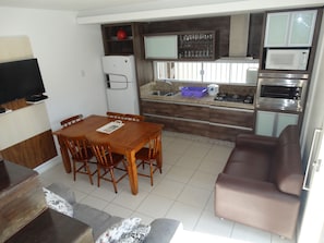 Cozinha compacta com mesa de jantar, cadeiras, sofá e eletrodomésticos embutidos.