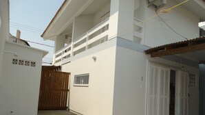 Un edificio a due piani con un balcone, un cancello in legno e una porta con persiane.