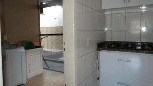 Uma cozinha com armários brancos, uma geladeira e um fogão.